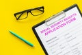 Social security benefits. Application form near pen and glasses on yellow background top view Royalty Free Stock Photo