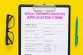 Social security benefits. Application form near pen and glasses on yellow background top view Royalty Free Stock Photo