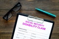 Social security. Disability claim form near glasses on dark wooden background top view
