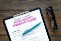 Social security. Disability claim form near glasses on dark wooden background top view