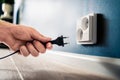 Socket, plug and electric power outlet. Man unplugging or holding cable wire cord in hand. Save energy. Royalty Free Stock Photo