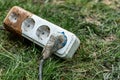 Socket, plug and electric white cable on the grass in the garden Royalty Free Stock Photo