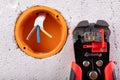 Socket in a raw wall with electric wires and electric insulation stripper. Repair of the electrical installation in the household Royalty Free Stock Photo