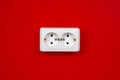 Socket on the red wall. Copy space. The concept of energy savings.  White electric socket on the red wall. Closeup Royalty Free Stock Photo