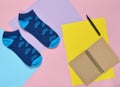 Socks, notebook on a colored paper background. Minimalism, top view. Royalty Free Stock Photo