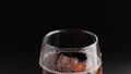 Soda fizzy cold drink in a glass with ice cubes close-up on a black background.