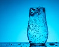 Soda mineral water in glass with ice, bubbles and droplets on the blue gradient background, concept of health and freshness Royalty Free Stock Photo