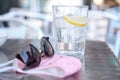 Soda water glass with ice and lemon. Sun glasses and face mask on the table. Royalty Free Stock Photo