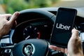 Soest, Germany - August 4, 2019: Uber driver holding smartphone in Volkswagen car. Uber is an American company offering