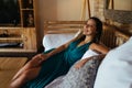 on the sofa among the pillows sitting in a long girl dress and smiling Royalty Free Stock Photo