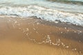 Soft beach sand with an incoming foam wave. Nature