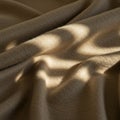 Soft, beige fabric with a textured surface is shown in draped folds. Sunlight creates a Royalty Free Stock Photo
