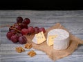 Soft blue cheese, ripe red grapes and walnuts on natural burlap backdrop Royalty Free Stock Photo