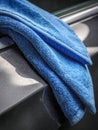 Soft blue microfiber cloth drying water droplets on a shiny dark surface after cleaning, emphasizing texture and car detailing Royalty Free Stock Photo
