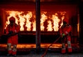 Soft blurred of two firefighter hold fire sprinkler and stand in front of group of fire in room