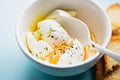 Soft boiled eggs with salt and thyme in white bowl on blue background