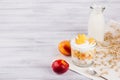 Soft breakfast with corn flakes, slice peach and milk bottle on white wood board.