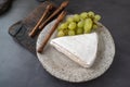 Soft brie camembert cheese with sweet grapes on a handmade clay plate. Top view, flat lay Royalty Free Stock Photo