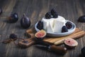 Soft cheese with brambles and fig halfs on a wooden rustic board. Close up dark moody shot, selective focus