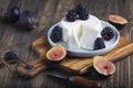 Soft cheese with brambles and fig halfs on a wooden rustic board. Close up dark moody shot, selective focus