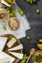 Soft cheese brie sliced on wooden cut with honey, pear, green green grapes and glass of white wine