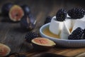 Soft cheese with honey, brambles and fig halfs on a wooden rustic board. Close up dark moody shot, selective focus