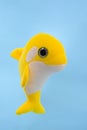 Soft children`s toy - yellow dolphin on blue background Royalty Free Stock Photo