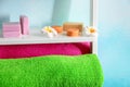 Soft color towels, flowers and soap on shelf near light wall, closeup