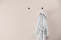 Soft comfortable bathrobe hanging on wall, space for text Royalty Free Stock Photo