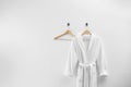 Soft comfortable bathrobe hanging on wall, space for text Royalty Free Stock Photo
