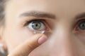 Soft contact lens on female finger against background of female eyes Royalty Free Stock Photo