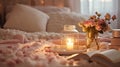 A soft, cozy bedroom setting with a lit candle on a tray, a fluffy pink blanket, an open book, and a vase of fresh flowers,