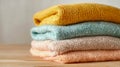 Soft and cozy pastel-colored knitted sweaters neatly folded in a stack on a wooden surface creating a warm and inviting atmosphere Royalty Free Stock Photo