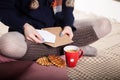 Soft cozy photo of slim tan woman in warm sweater on the bed with cup of tea in hands, top view point. Composition with Royalty Free Stock Photo