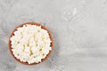 Soft curd natural healthy food, wholesome diet food. Homemade cottage cheese in a clay bowl on a gray neutral background, top view