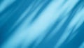 Soft, diagonal shadows create an abstract, flowing pattern on a blue backdrop