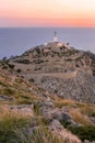 Soft dreamy purple pink morning dawn sunrise vertical pic of cap de formentor light house on dry rocky sand cliff with yellow dry Royalty Free Stock Photo