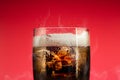 Soft drink glass with ice splash on cool smoke background. Cola glass with summer refreshment