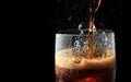 Soft drink glass with ice splash on dark background. Cola glass in celebration party concept. Royalty Free Stock Photo