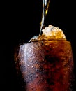 Soft drink pouring to glass with ice isolated on dark background Royalty Free Stock Photo