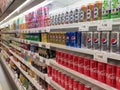 Soft drinks in cans are displayed on a shelf for sale in a large supermarket.