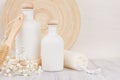 Soft elegant bathroom decor of white cosmetics bottles with comb, flowers on white wood board, mock up, copy space.