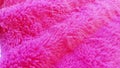 Soft faux fur of bright pink or fuchsia, laid in waves. Sample material for clothing, plush toys, plaids, bedspreads, covers and
