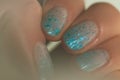 Female mood. Shiny glitter gradient nails design. Beautiful nail art with blue tinsel. Closeup photo with grease effect