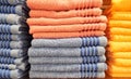 Soft fiber towels of blue and orange on a shelf in the store. Pile of towels