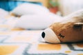 A soft fluffy bear toy lies on a nice yellow bedspread on the bed