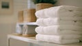 Soft fluffy white towels are neatly folded and stacked on a nearby shelf Royalty Free Stock Photo