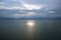 Soft focus abstract morning foggy time mountain silhouette landscape in calm sea bay water surface with reflection of sun rise Royalty Free Stock Photo