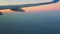 Soft focus airial view on airplane wing above blue land and white fog against pink sky