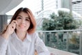 Soft focus of attractive young Asian business woman talking on phone in office with copy space background. Royalty Free Stock Photo